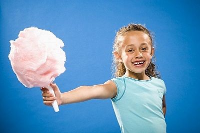 bambina che mangia lo zucchero filato fatto dalla macchina professionale
