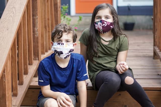 Bambini seduti sulle scale con mascherina per corona virus